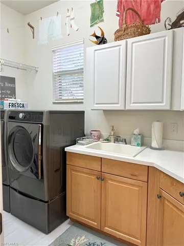 Washroom featuring separate washer and dryer, sink, and cabinets