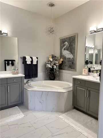 Bathroom with tile patterned flooring, tiled tub, and vanity