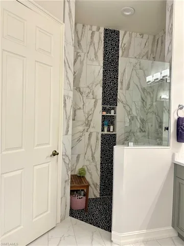 Bathroom with vanity, tile patterned flooring, and a tile shower