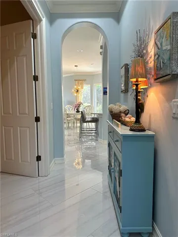 Corridor featuring crown molding, a chandelier, and light tile patterned floors