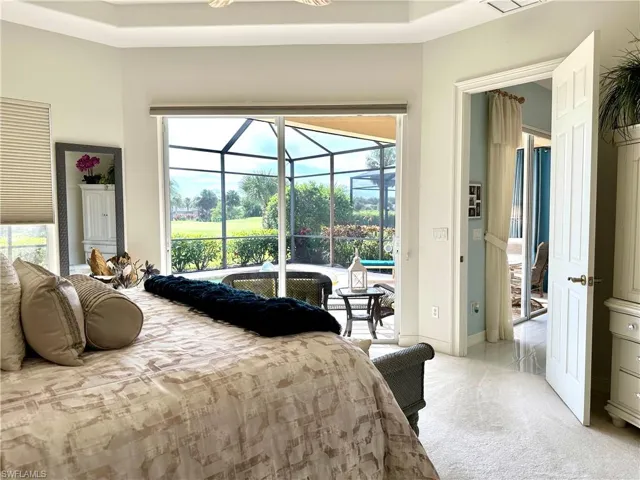 Carpeted bedroom featuring access to exterior and a tray ceiling