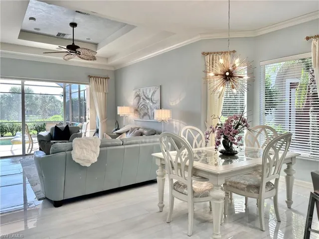 Dining space with ceiling fan with notable chandelier, crown molding, and a tray ceiling