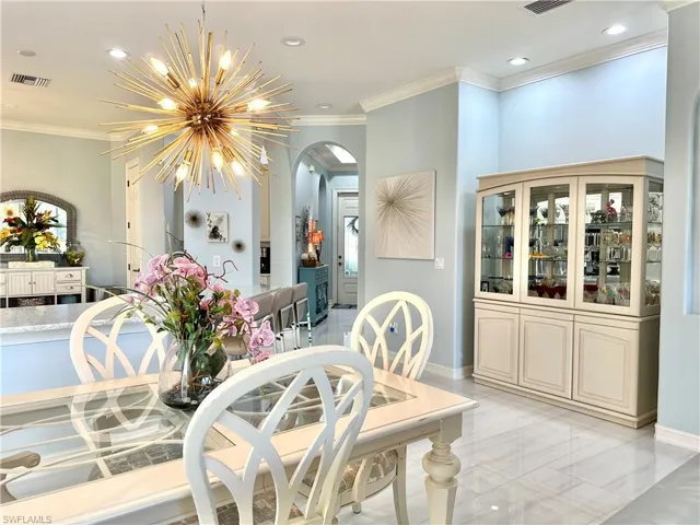 Tiled dining area featuring a notable chandelier and ornamental molding