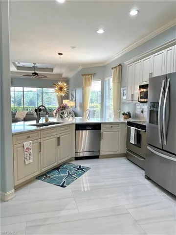 Kitchen with appliances with stainless steel finishes, a wealth of natural light, light tile patterned floors, and crown molding