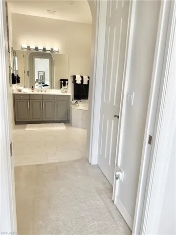 Bathroom featuring vanity, tile patterned flooring, and a relaxing tiled tub