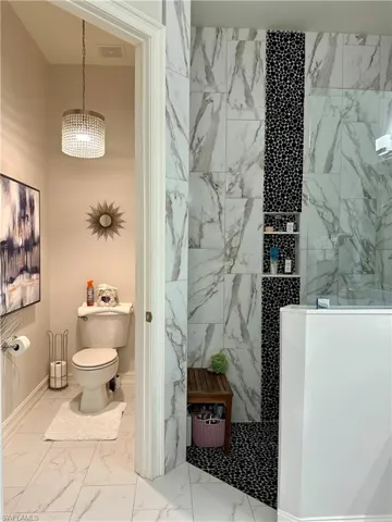 Bathroom with tiled shower, tile patterned floors, and toilet