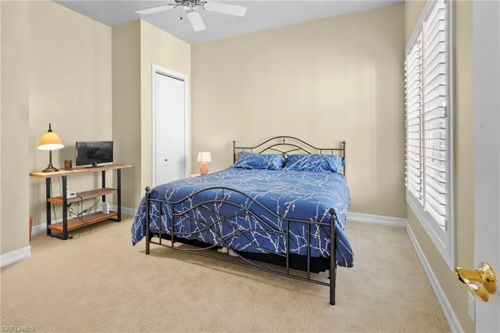 Carpeted bedroom with ceiling fan and a closet