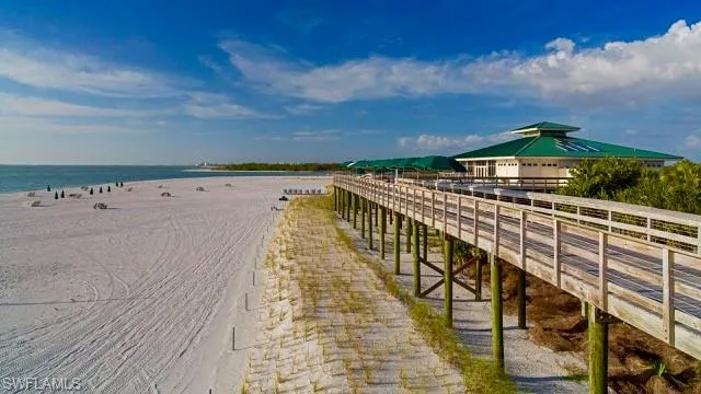 Surrounding community featuring a pier and view of water and beach