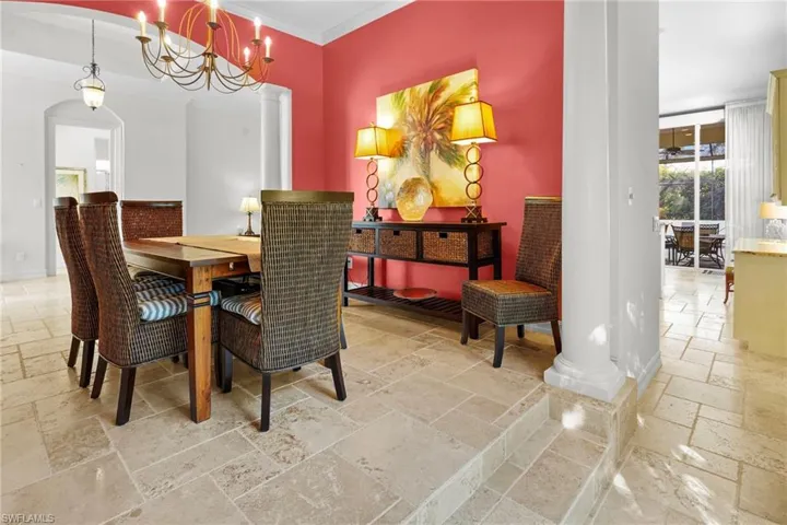 Dining space featuring stone tile flooring, a chandelier, crown molding, and arched walkways