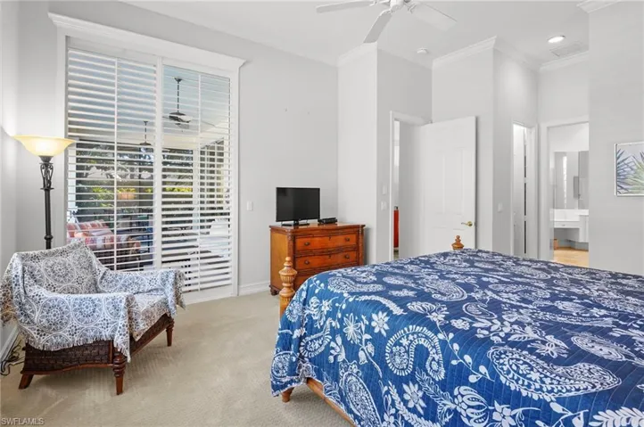 Bedroom featuring ornamental molding, carpet flooring, access to exterior, a ceiling fan, and ensuite bath
