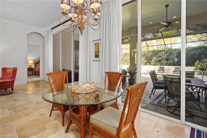 Dining room featuring arched walkways, stone tile floors, a chandelier, crown molding, and a ceiling fan