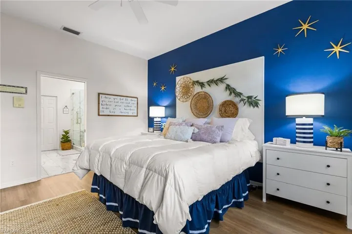Bedroom with wood-type flooring, ensuite bathroom, and ceiling fan