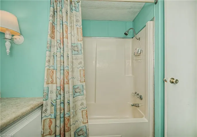 Full bath with shower / bath combo with shower curtain, a textured ceiling, and vanity