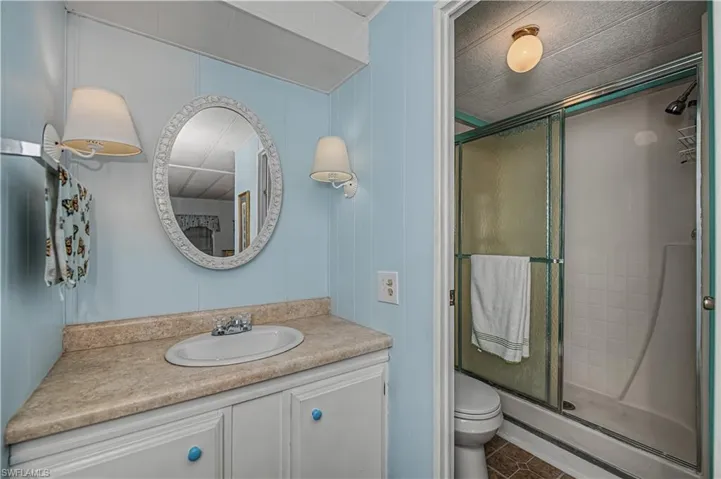 Bathroom with vanity, a stall shower, a decorative wall, and dark tile patterned floors