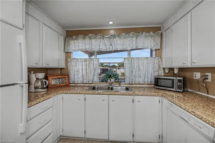 Kitchen featuring white appliances and white cabinetry