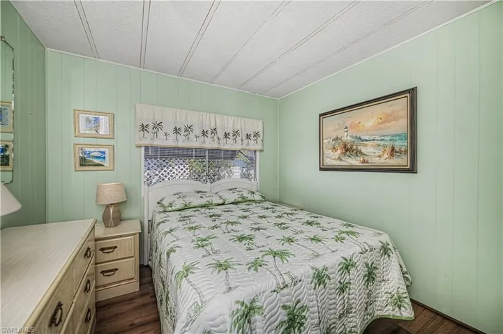 Bedroom with wood walls, a textured ceiling, and dark wood-style floors