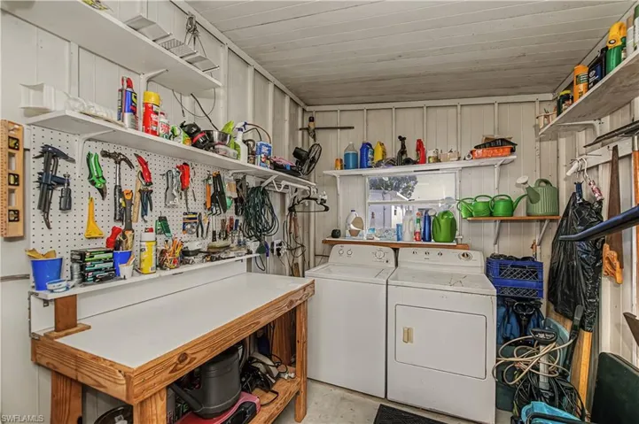 Laundry room with concrete flooring, washer and clothes dryer, and a workshop area