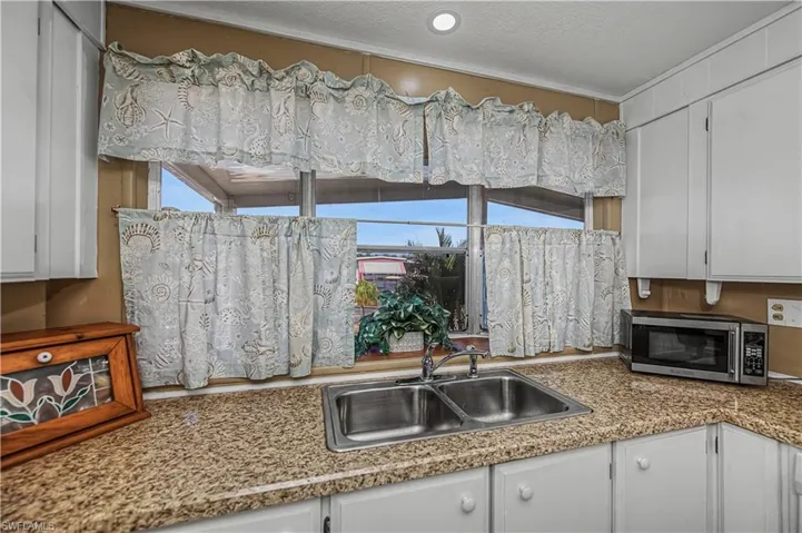 Kitchen with white cabinetry, light countertops, stainless steel microwave, and a textured ceiling