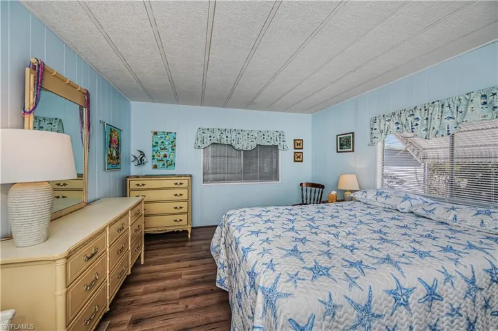 Bedroom featuring dark wood-type flooring, a textured ceiling, and wood walls