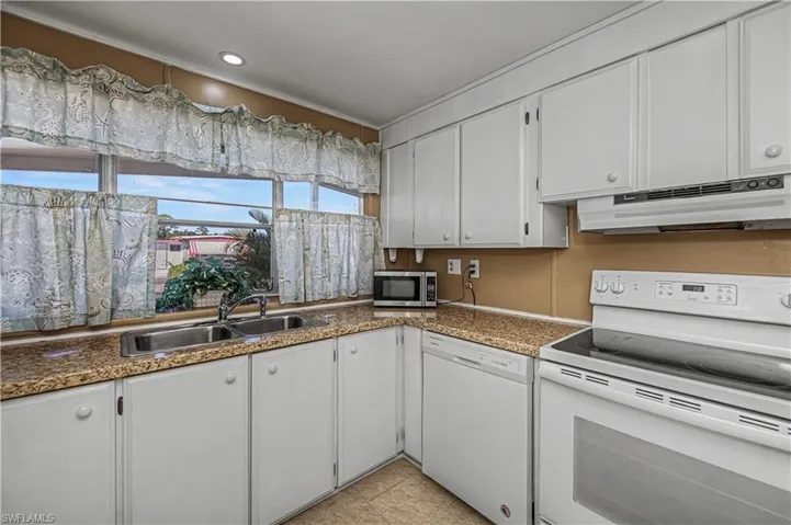 Kitchen featuring white appliances, white cabinetry, and recessed lighting