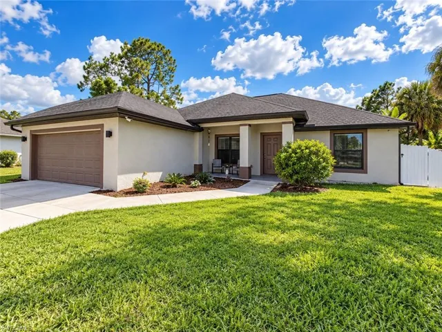 Stucco exterior residence featuring a covered entryway, a two-car garage with a paneled door, a shingle roof, and a concrete driveway