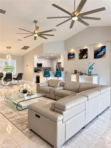 Open-concept interior featuring vaulted ceilings, oversized ceiling fans with integrated lighting, polished tile flooring, and recessed accent lighting