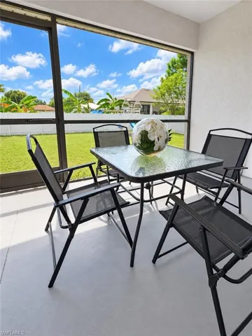Screen-enclosed covered patio featuring concrete flooring and a white vinyl perimeter fence