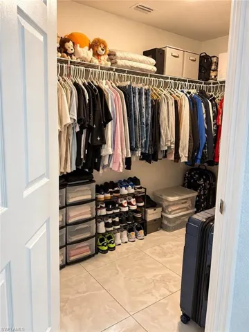 Walk-in closet featuring large-format tile flooring and tiered wire shelving
