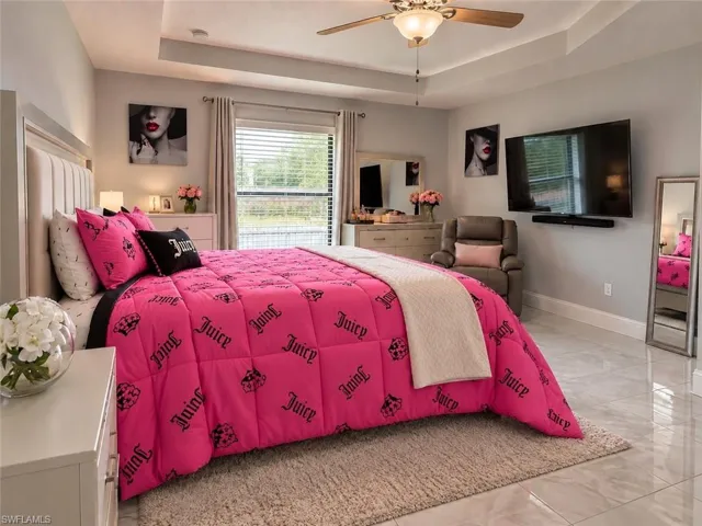Tray ceiling with central flush-mount light fixture and ceiling fan, large-format tile flooring, and oversized window with neutral drapery