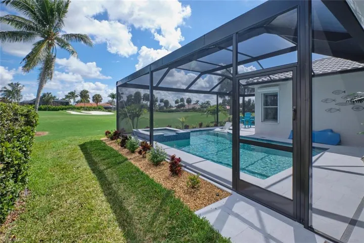 View of pool with glass enclosure, a yard, an in ground hot tub, and a patio
