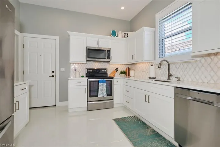 Kitchen with white cabinets, backsplash, stainless steel appliances, and sink