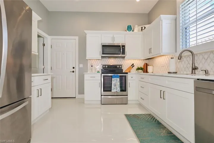 Kitchen featuring white cabinets, sink, stainless steel appliances, and tasteful backsplash