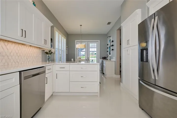 Kitchen with kitchen peninsula, white cabinetry, stainless steel appliances, and tasteful backsplash