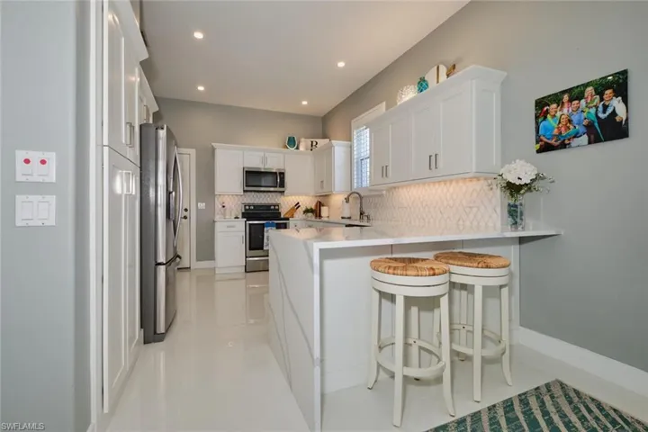 Kitchen with white cabinets, a breakfast bar, kitchen peninsula, and stainless steel appliances