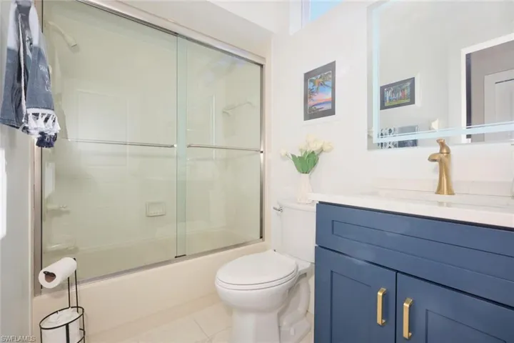 Full bathroom featuring tile patterned floors, vanity, enclosed tub / shower combo, and toilet