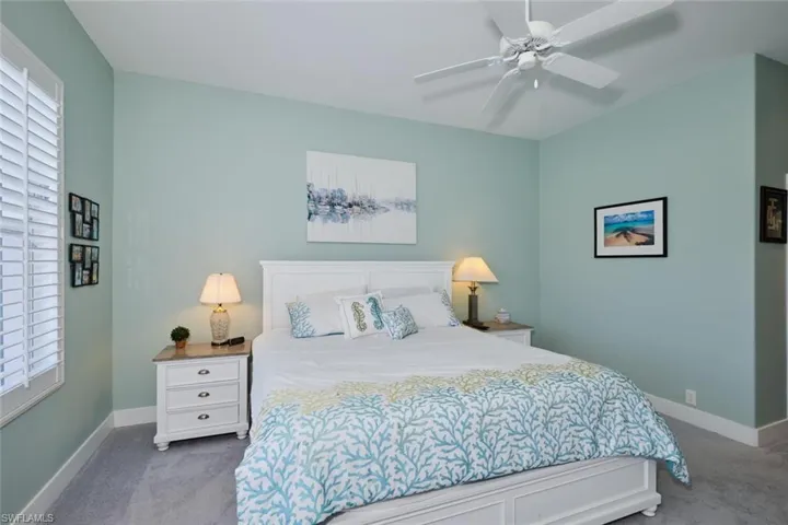 Carpeted bedroom featuring ceiling fan and multiple windows