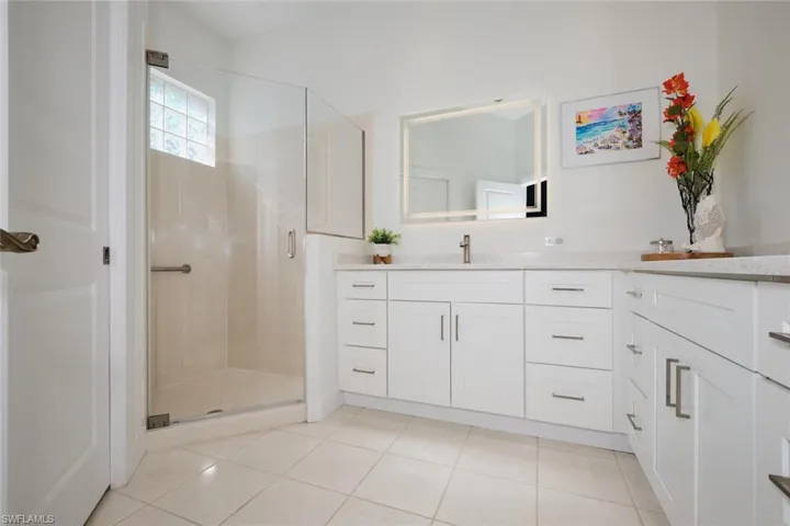 Bathroom featuring tile patterned flooring, vanity, and an enclosed shower