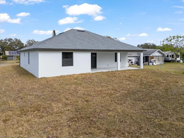 Rear view of property with a lawn and a patio area