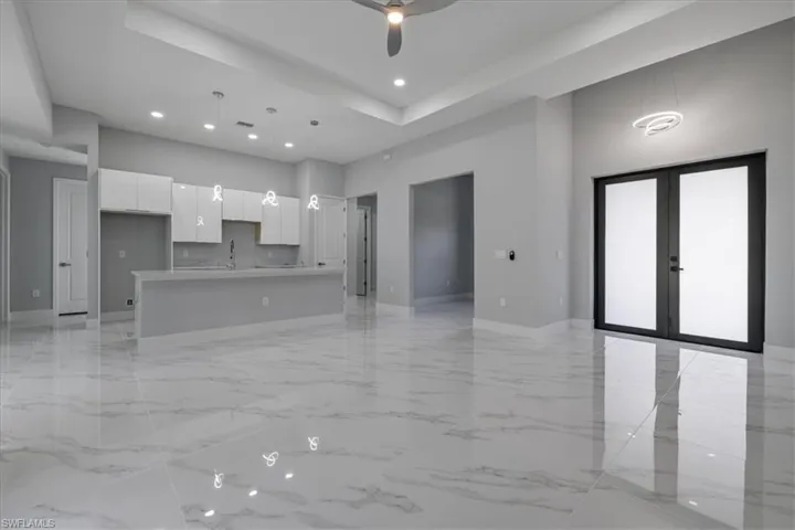 Unfurnished living room featuring ceiling fan, french doors, and sink