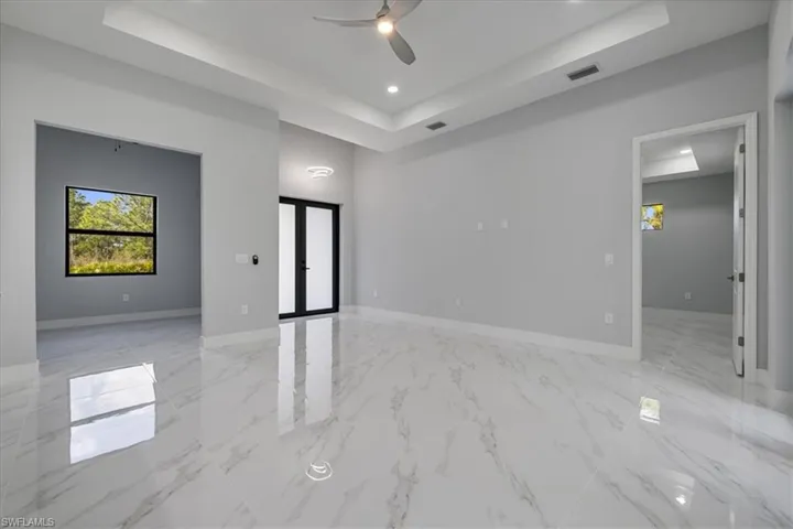 Empty room with french doors, a tray ceiling, and ceiling fan