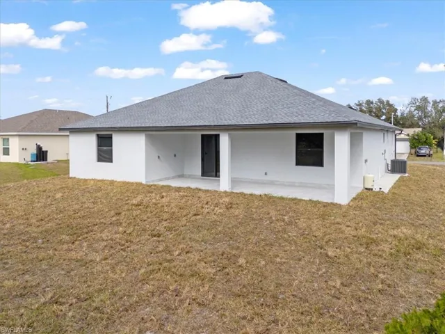Back of property featuring central AC unit, a patio area, and a yard