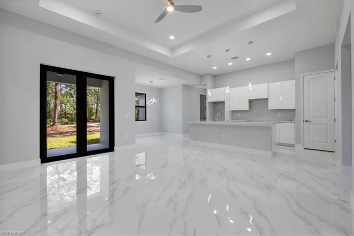 Unfurnished living room featuring ceiling fan, a raised ceiling, and sink