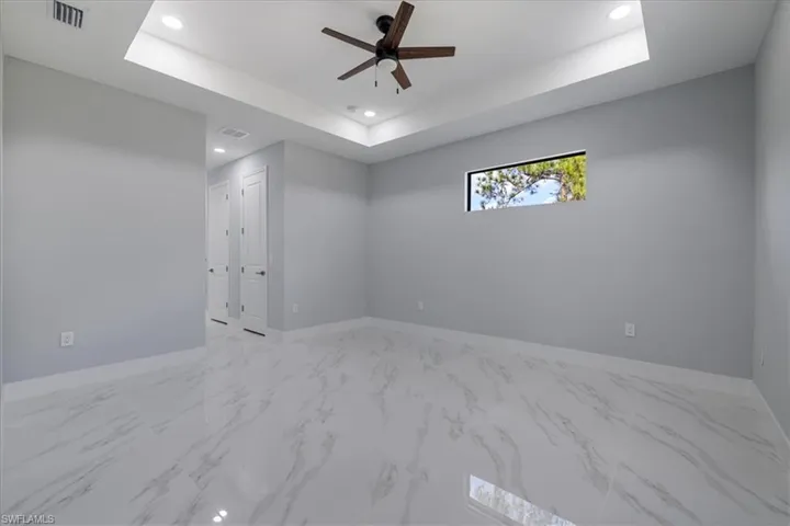 Unfurnished room featuring a raised ceiling and ceiling fan