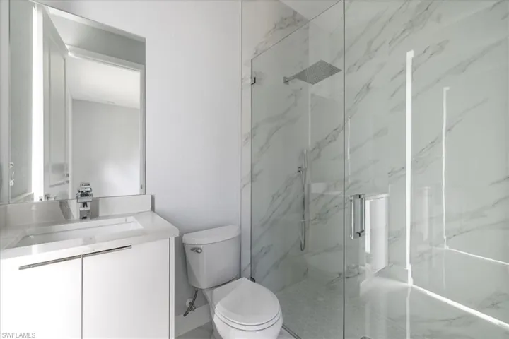 Bathroom with vanity, a shower with shower door, and toilet