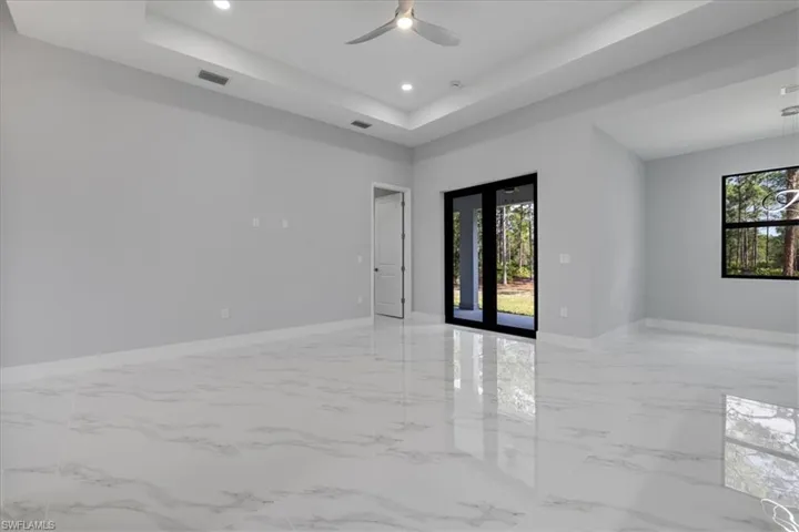 Unfurnished room with ceiling fan and a tray ceiling