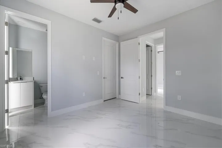 Unfurnished bedroom with ensuite bath and ceiling fan