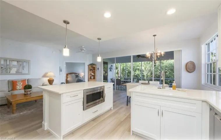 Kitchen featuring open floor plan, white cabinetry, hanging light fixtures, stainless steel appliances, and ceiling fan