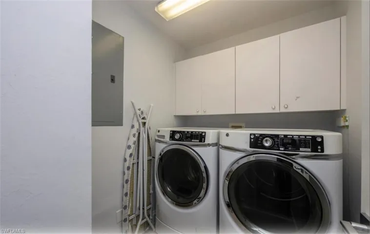 Washroom featuring electric panel, separate washer and dryer, and cabinet space