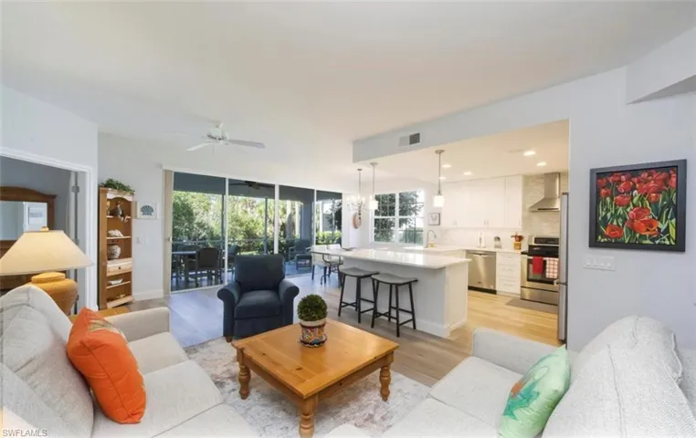 Living room featuring light wood-style floors, expansive windows, a chandelier, and a ceiling fan