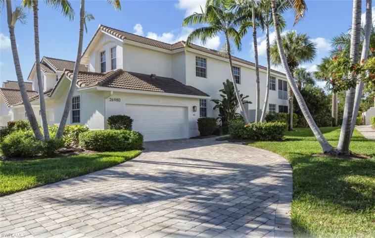 View of front of property with stucco siding, a front yard, decorative driveway, a tiled roof, and a garage